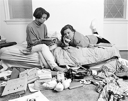 1980s TWO TEENAGE AFRICAN AMERICAN GIRLS IN CLUTTERED BEDROOM ONE TALKING ON THE PHONE ONE READING MAGAZINE Foto de stock - Con derechos protegidos, Código: 846-08226115