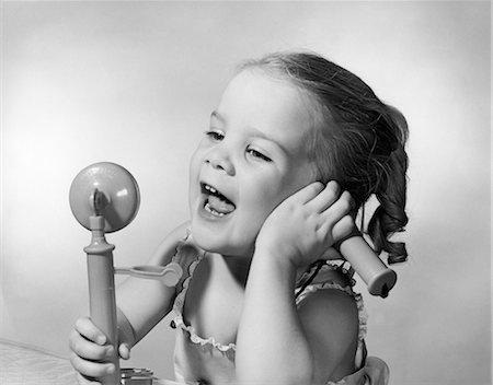 simsearch:846-05648448,k - 1950s HAPPY LITTLE GIRL TALKING INTO TOY TELEPHONE Foto de stock - Direito Controlado, Número: 846-08226126