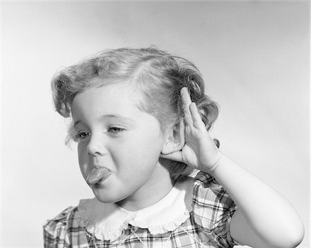 1950s LITTLE GIRL MAKING RUDE GESTURE STICKING OUT TONGUE CUPPING HAND ON EAR Foto de stock - Con derechos protegidos, Código: 846-08226121