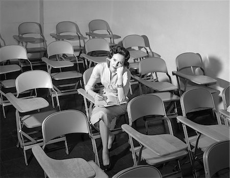 1950s WOMAN SITTING IN CLASSROOM OF EMPTY CHAIRS ANNOYED Fotografie stock - Rights-Managed, Codice: 846-08226175