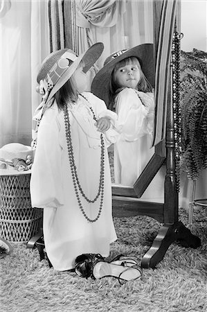 simsearch:846-05646482,k - 1980s LITTLE GIRL DRESSED UP IN ADULT CLOTHES POSING BEFORE MIRROR FUN PLAY ROLE PLAYING HAT BEAD NECKLACE Fotografie stock - Rights-Managed, Codice: 846-08512702