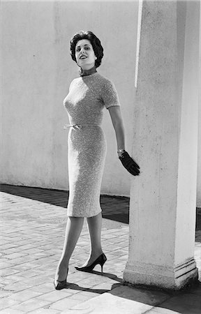 1960s FULL LENGTH PORTRAIT WOMAN WEARING TIGHT KNITTED DRESS LEATHER GLOVES POSING BY COLUMN OUTDOORS LOOKING AT CAMERA Foto de stock - Con derechos protegidos, Código: 846-08639496