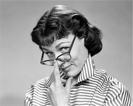1950s 1960s BRUNETTE WOMAN WEARING EYE GLASSES LOOKING UP WITH DOUBTFUL SKEPTICAL EXPRESSION LOOKING AT CAMERA Foto de stock - Con derechos protegidos, Código: 846-08639505