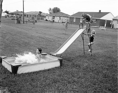 simsearch:846-03163739,k - 1950s THREE GIRLS PLAYING SLIDING DOWN SLIDE INTO SWIMMING POOL SUMMER Stockbilder - Lizenzpflichtiges, Bildnummer: 846-08639535