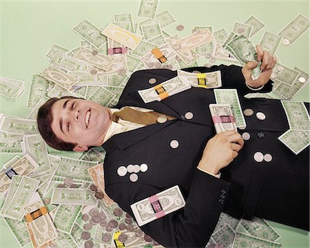 1960s SMILING MAN LYING ON FLOOR COVERED WITH FAKE MONEY Photographie de stock - Rights-Managed, Code: 846-08639552