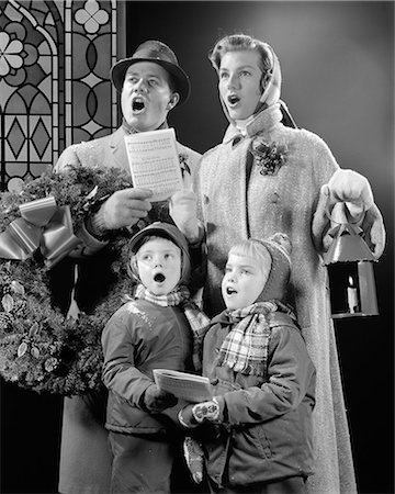 1950s FAMILY OF FOUR SON DAUGHTER SINGING CHRISTMAS CAROLS DAD HOLDING WREATH MOM HOLDING CANDLE LANTERN Stockbilder - Lizenzpflichtiges, Bildnummer: 846-08721140