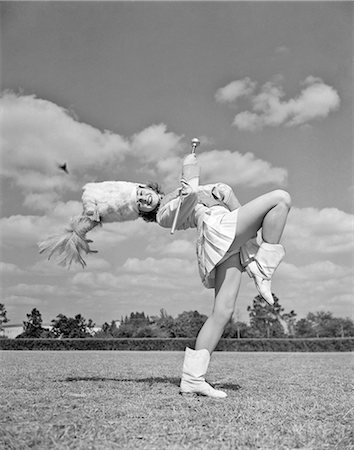 excité (sensuel) - 1940s 1950s TEENAGED GIRL MAJORETTE MARCHING ACROSS FIELD WITH BATON KICKING UP ONE LEG Stock Photo - Rights-Managed, Code: 846-09012688