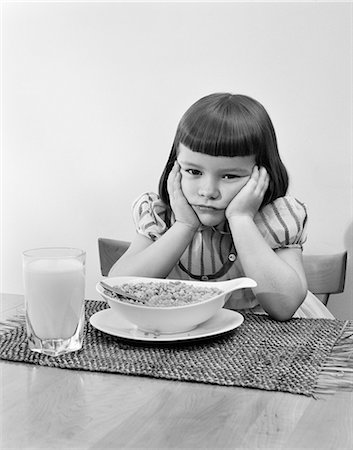 1950s GRUMPY GIRL SITTING AT TABLE WITH BOWL OF CEREAL GLASS OF MILK LEANING CHIN ON HANDS Stock Photo - Rights-Managed, Code: 846-09012689
