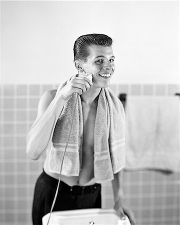 rasierapparat - 1950s SMILING TEENAGED BOY STANDING AT BATHROOM SINK SHAVING WITH ELECTRIC RAZOR LOOKING AT CAMERA Stockbilder - Lizenzpflichtiges, Bildnummer: 846-09012697