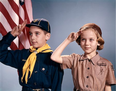 simsearch:846-05646460,k - 1960s BOY AND GIRL IN CUB SCOUT AND BROWNIE UNIFORMS STANDING BY AMERICAN FLAG SALUTING Stock Photo - Rights-Managed, Code: 846-09012830