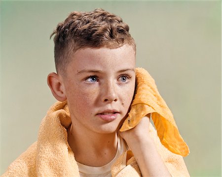 1960s ADOLESCENT YOUTHFUL BOY WITH BLUE EYES CURLY HAIR AND FRECKLES WASHING FACE WITH WASH CLOTH AND TOWEL Foto de stock - Con derechos protegidos, Código: 846-09012847