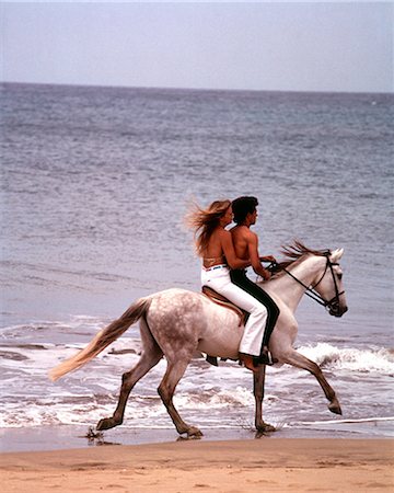 riding on horses on the beach - 1970s MAN WOMAN COUPLE RIDING TOGETHER ON SINGLE WHITE GRAY HORSE ON BEACH Stock Photo - Rights-Managed, Code: 846-09012927