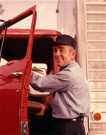 1950s 1960s SMILING MAN DELIVERY DRIVER WEARING CAP AND UNIFORM LOOKING AT CAMERA STEPPING INTO CAB THROUGH OPEN TRUCK DOOR Stockbilder - Lizenzpflichtiges, Bildnummer: 846-09012959