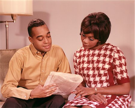 1960s AFRICAN AMERICAN COUPLE HUSBAND POINTING OUT NEWSPAPER ARTICLE TO WIFE Photographie de stock - Rights-Managed, Code: 846-09012964