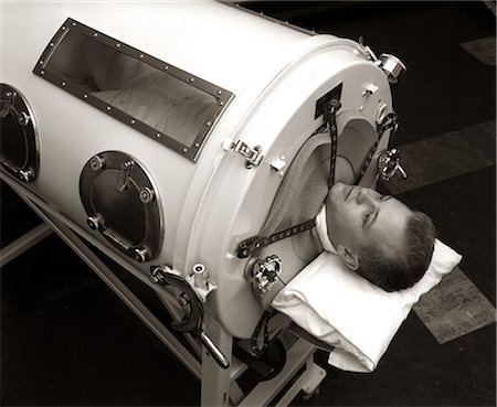 1930s 1940s 1950s MAN LYING IN IRON LUNG NEGATIVE PRESSURE VENTILATOR ARTIFICIAL BREATHING MACHINE Photographie de stock - Rights-Managed, Code: 846-09013072