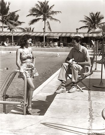 1930s COUPLE TROPICAL HOTEL SWIMMING POOL SIDE WOMAN BATHING SUIT MAN SITTING DIRECTORS CHAIR CASUAL CLOTHES MIAMI BEACH FL USA Photographie de stock - Rights-Managed, Code: 846-09013117
