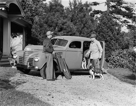 simsearch:846-03163283,k - 1930s TWO MEN STANDING BY FOUR DOOR SEDAN PACKING GUNS HUNTING GEAR AND TWO SPRINGER SPANIEL DOGS Photographie de stock - Rights-Managed, Code: 846-09085283