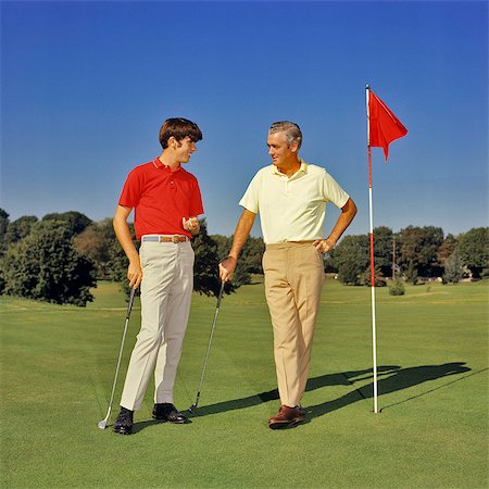 1960s 1970s TEENAGE BOY AND MIDDLEAGED FATHER ON GOLF COURSE GREEN LEANING ON CLUBS TALKING Photographie de stock - Rights-Managed, Code: 846-09085329