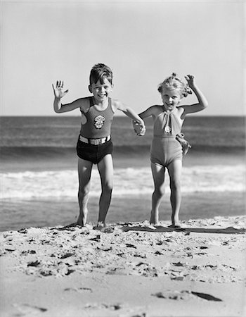 1930s TWO KIDS BOY GIRL HOLDING HANDS RUNNING ON SANDY BEACH Foto de stock - Con derechos protegidos, Código: 846-09161414