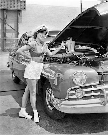 1950s SMILING WOMAN POSING WEARING SHORTS ADDING OIL TO CAR ENGINE LOOKING AT CAMERA Stock Photo - Rights-Managed, Code: 846-09161426