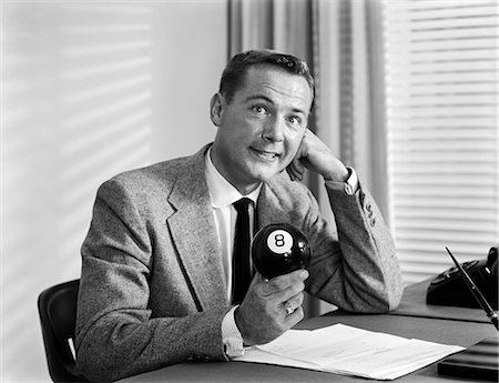 sans issue - 1950s WORRIED BUSINESSMAN SITTING AT DESK BEHIND BLACK EIGHT BALL LOOKING AT CAMERA Photographie de stock - Rights-Managed, Code: 846-09161422