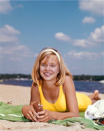 1960s SMILING TEEN GIRL LAYING ON BEACH TOWEL HOLDING TRANSISTOR RADIO WEARING YELLOW BATHING SUIT LOOKING AT CAMERA Foto de stock - Con derechos protegidos, Código: 846-09161454