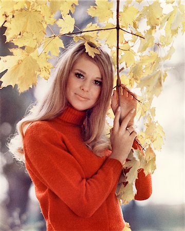 1960s YOUNG WOMAN LOOKING AT CAMERA WEARING PRETTY RED FASHION STYLE TURTLENECK SWEATER HOLDING BRANCH OF AUTUMN LEAVES Stock Photo - Rights-Managed, Code: 846-09161476