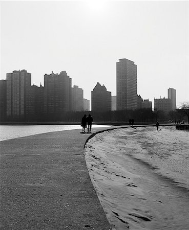 1960s TWO ANONYMOUS SILHOUETTED PEOPLE WALKING ALONG LAKE SHORE CHICAGO ILLINOIS USA Stock Photo - Rights-Managed, Code: 846-09161593