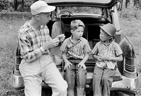 1960s MAN FATHER AND TWO BOYS SONS TWINS SITTING ON REAR BUMPER OF CAR PREPARING FISHING GEAR Foto de stock - Con derechos protegidos, Código: 846-09181476