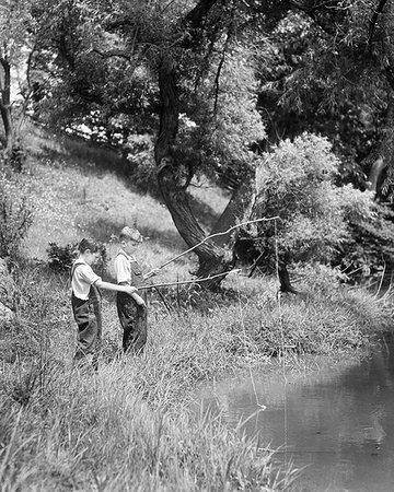 1930s TWO BOYS FISHING WITH STICK AND STRING FISHING RODS ON BRIGHT SUMMER DAY Stock Photo - Rights-Managed, Code: 846-09181480