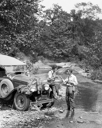 1920s COUPLE FLY FISHING MAN STANDING IN STREAM WOMAN SITTING  ON FENDER OF CAR Stock Photo - Rights-Managed, Code: 846-09181497