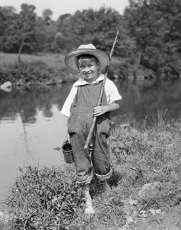 1920s 1930s BAREFOOT BOY CARRYING STICK FISHING ROD CAN OF BAIT WORMS WEARING STRAW HAT BIB OVERALLS LOOKING AT CAMERA SMILING Photographie de stock - Rights-Managed, Code: 846-09181508
