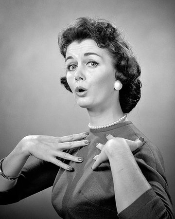 simsearch:846-08639543,k - 1950s 1960s BRUNETTE WOMAN PEARL STRAND SURPRISED EXPRESSION MAKING WHO ME GESTURE HANDS TO CHEST LOOKING AT CAMERA Photographie de stock - Rights-Managed, Code: 846-09181646