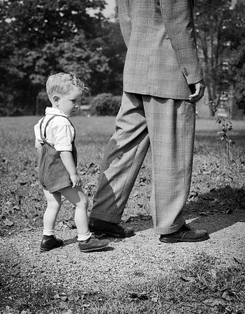 simsearch:846-09181548,k - 1940s BOY FOLLOWING BEHIND MAN WALKING IN HIS FATHER'S FOOTSTEPS Stockbilder - Lizenzpflichtiges, Bildnummer: 846-09181666