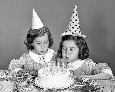 1960s TWIN GIRLS WEARING PARTY HATS BLOWING OUT CANDLES ON BIRTHDAY CAKE Stock Photo - Rights-Managed, Code: 846-09181674