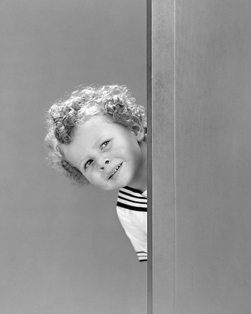 1940s CURLY BLOND HAIR LITTLE BOY IN SAILOR SUIT PEEKING AROUND CORNER LOOKING AT CAMERA Foto de stock - Con derechos protegidos, Código: 846-09181706