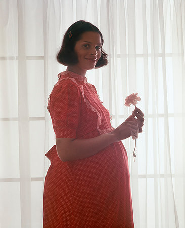 simsearch:846-09181487,k - 1970s PREGNANT AFRICAN AMERICAN WOMAN LOOKING AT CAMERA SILHOUETTED PROFILE AGAINST SHEER WINDOW LIGHT HOLDING FLOWER SMILING Foto de stock - Con derechos protegidos, Código: 846-09181861