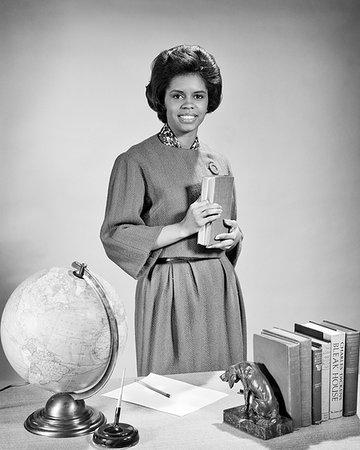 simsearch:846-09181487,k - 1960s SMILING AFRICAN AMERICAN WOMAN TEACHER AT HER DESK HOLDING TEXTBOOKS LOOKING AT CAMERA Foto de stock - Con derechos protegidos, Código: 846-09181926