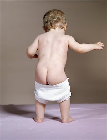 1960s BACK VIEW OF BABY WITH FALLING DOWN DIAPER SHOWING BABY'S BARE BOTTOM Foto de stock - Direito Controlado, Número: 846-02794006