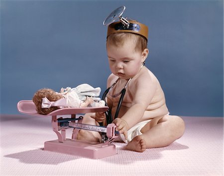 doctor vintage - BABY WITH PHYSICIAN MIRROR HEADBAND WEIGHING DOLL ON INFANT BALANCE SCALE STUDIO Stock Photo - Rights-Managed, Code: 846-02794015