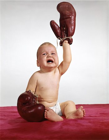 ANNÉES 1960 GANTS DE BOXE DE PORTER BÉBÉ QUI PLEURE UN BRAS DE PORTE VERS LE HAUT Photographie de stock - Rights-Managed, Code: 846-02794062