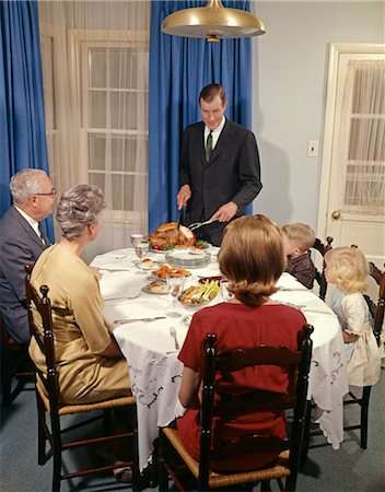 family dining vintage - THREE GENERATION FAMILY SITTING AT TABLE FATHER CARVING ROAST CHICKEN INDOOR MAN WOMAN BOY GIRL Stock Photo - Rights-Managed, Code: 846-02794158