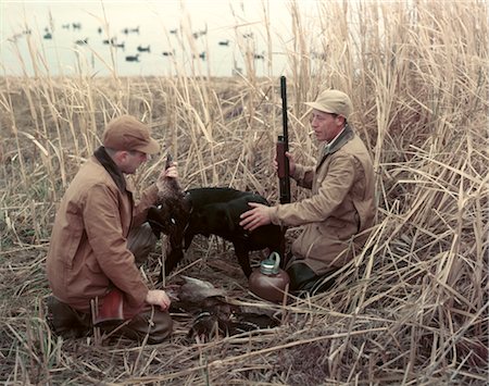 simsearch:846-05646808,k - 1950s TWO MEN BLACK DOG RETRIEVER IN TALL GRASS REEDS AT EDGE OF LAKE DUCK DECOYS AUTUMN WATER FOWL SPORT Foto de stock - Con derechos protegidos, Código: 846-02794184