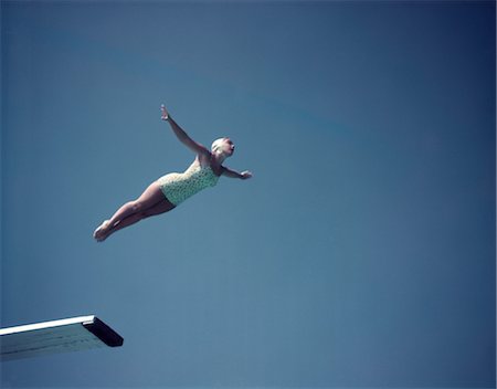 sports 1950s - 1950s WOMAN WEARING WHITE ONE PIECE BATHING SUIT AND CAP SWAN DIVING OFF HIGH BOARD AGAINST BLUE SKY Stock Photo - Rights-Managed, Code: 846-02794189