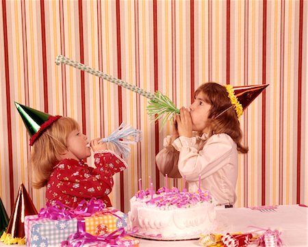 party indoors retro - 1970 1970s TWO GIRLS PARTY HATS NOISE MAKERS FAVORS BIRTHDAY CAKE CELEBRATE CELEBRATION PARTIES CAKES HAPPY Foto de stock - Con derechos protegidos, Código: 846-02794585