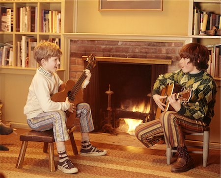 1970 1970s 2 BOYS FRONT FIREPLACE PLAY PLAYING STRUMMING GUITARS CHILDREN BOY CHILD MUSIC LIVING ROOM STOOLS Stock Photo - Rights-Managed, Code: 846-02794786