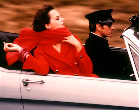 sports car - 1970s STYLISH WOMAN IN RED DRESS AND SCARF RIDING IN OPEN AIR CONVERTIBLE SPORTS CAR DRIVEN BY CHAUFFEUR Stock Photo - Rights-Managed, Code: 846-02794790