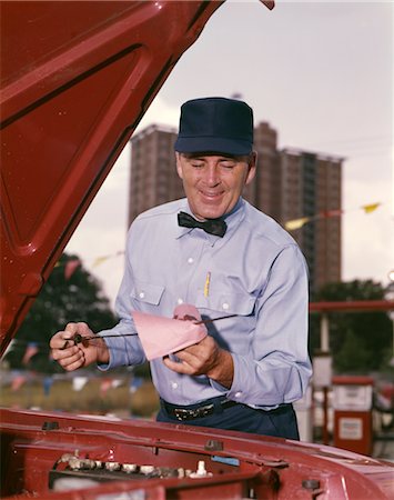 PRÉPOSÉ DE STATION-SERVICE GARAGE DES ANNÉES 1960 DANS VÉRIFICATION UNIFORME HUILE AUTOMOBILE DIP STICK Photographie de stock - Rights-Managed, Code: 846-02794842