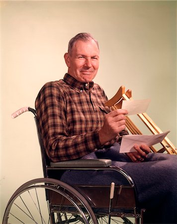 1960s SENIOR MATURE MAN SMILING HOLDING INSURANCE CHECK WHEELCHAIR CRUTCHES Stock Photo - Rights-Managed, Code: 846-02794860