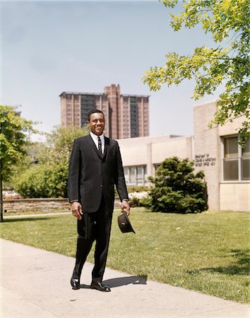 HOMME D'AFFAIRES AFRO-AMÉRICAIN DES ANNÉES 1960 PORTE-DOCUMENTS ET CHAPEAU EN MARCHANT SUR LE TROTTOIR URBAIN Photographie de stock - Rights-Managed, Code: 846-02794886